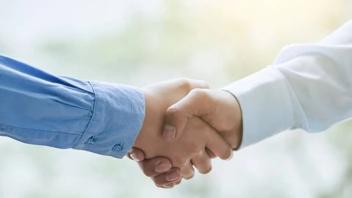 Dos personas estrechándose la mano, simbolizando confianza, seguridad y buena gestión profesional en una comunidad de propietarios.