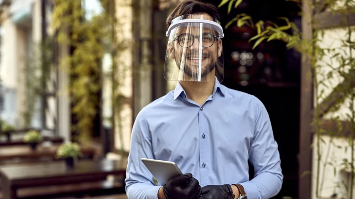 Trabajador con casco y pantalla de protección en un entorno laboral, representando la coordinación de actividades empresariales y la prevención de riesgos.