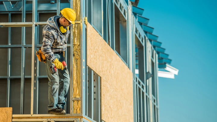 Trabajador con equipo de seguridad realizando tareas en altura en la fachada de un edificio.