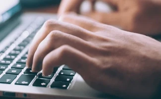 Persona escribiendo en un portátil, representando los retos y oportunidades de la transformación digital en asesorías.