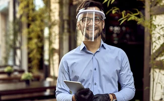 Trabajador con casco y pantalla de protección en un entorno laboral, representando la coordinación de actividades empresariales y la prevención de riesgos.